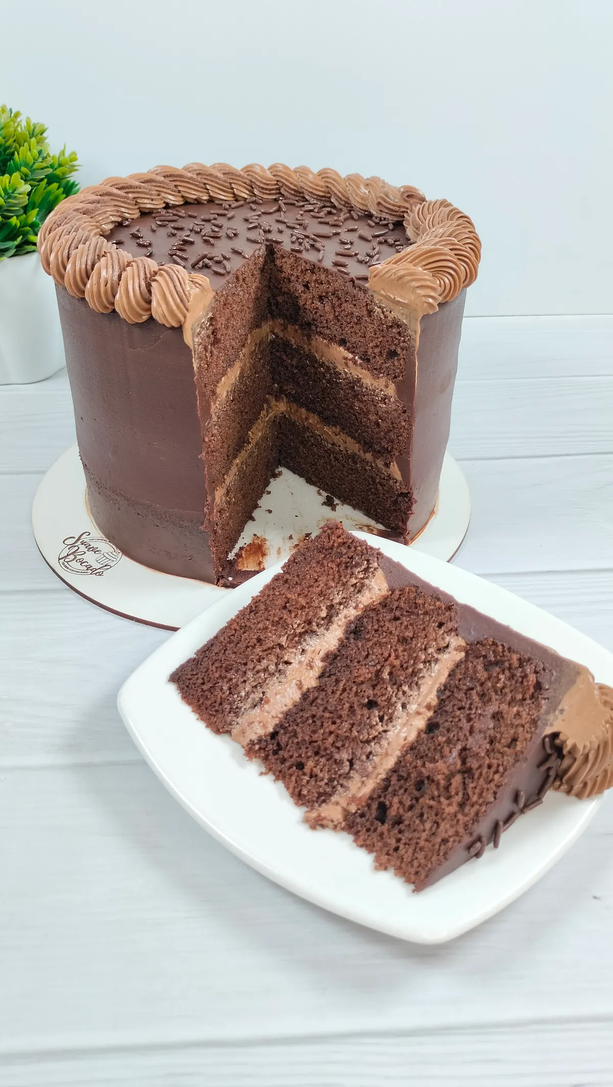 Torta de chocolate de tres capas, abierta, con una porción servida que deja ver el relleno