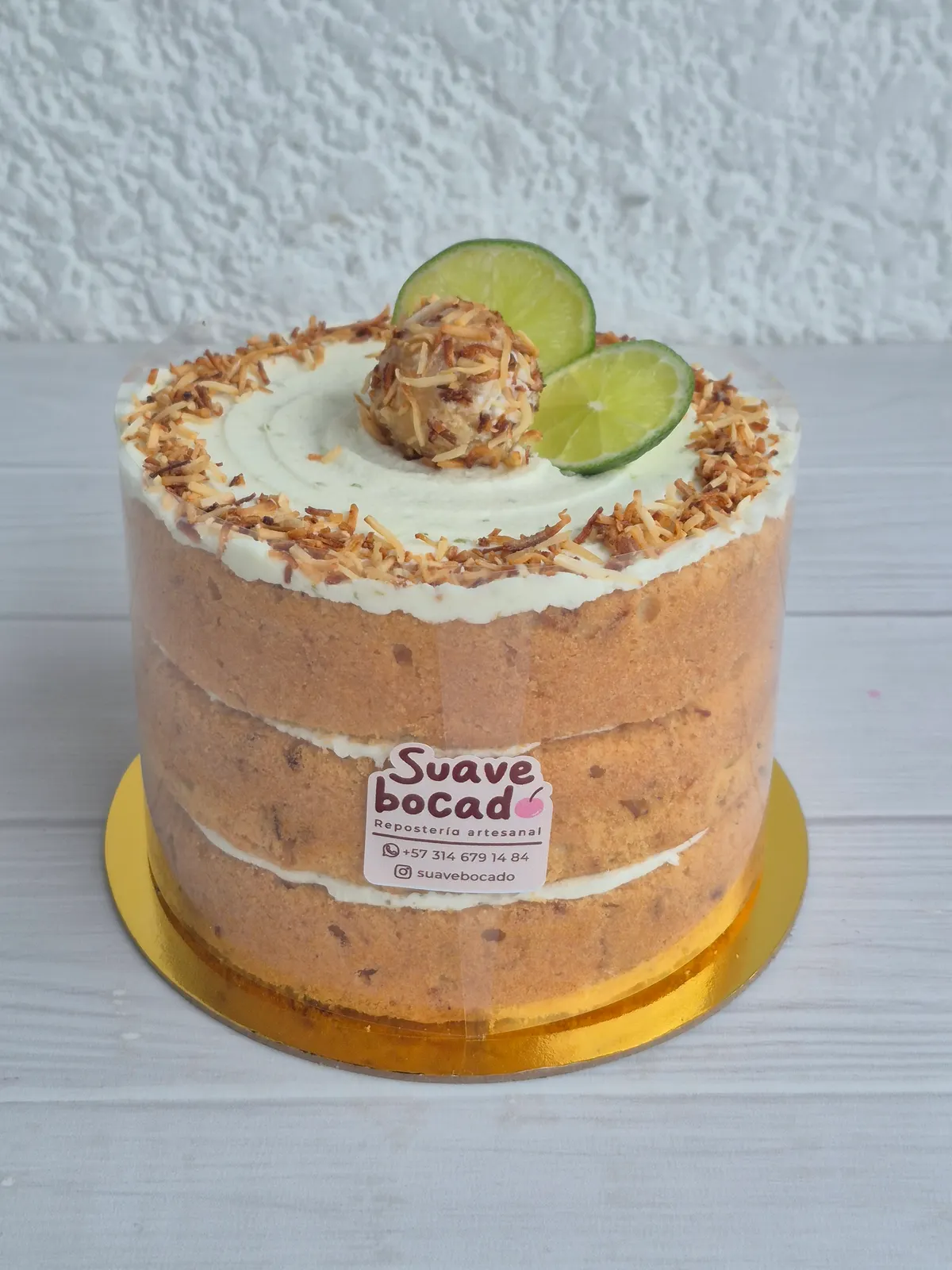 Torta alta de tres capas a la vista con coco tostado, rodajas de limón y una trufa encima