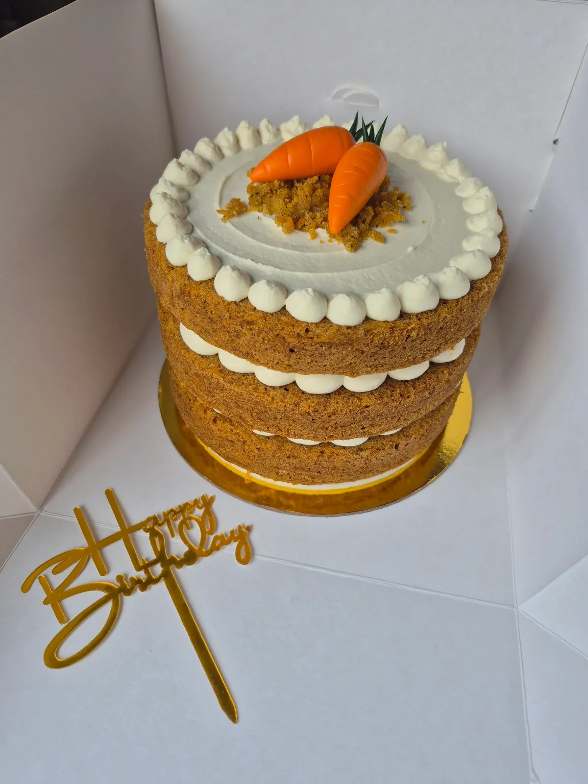 Torta de capas a la vista con crema, decorada con dos zanahorias de azúcar