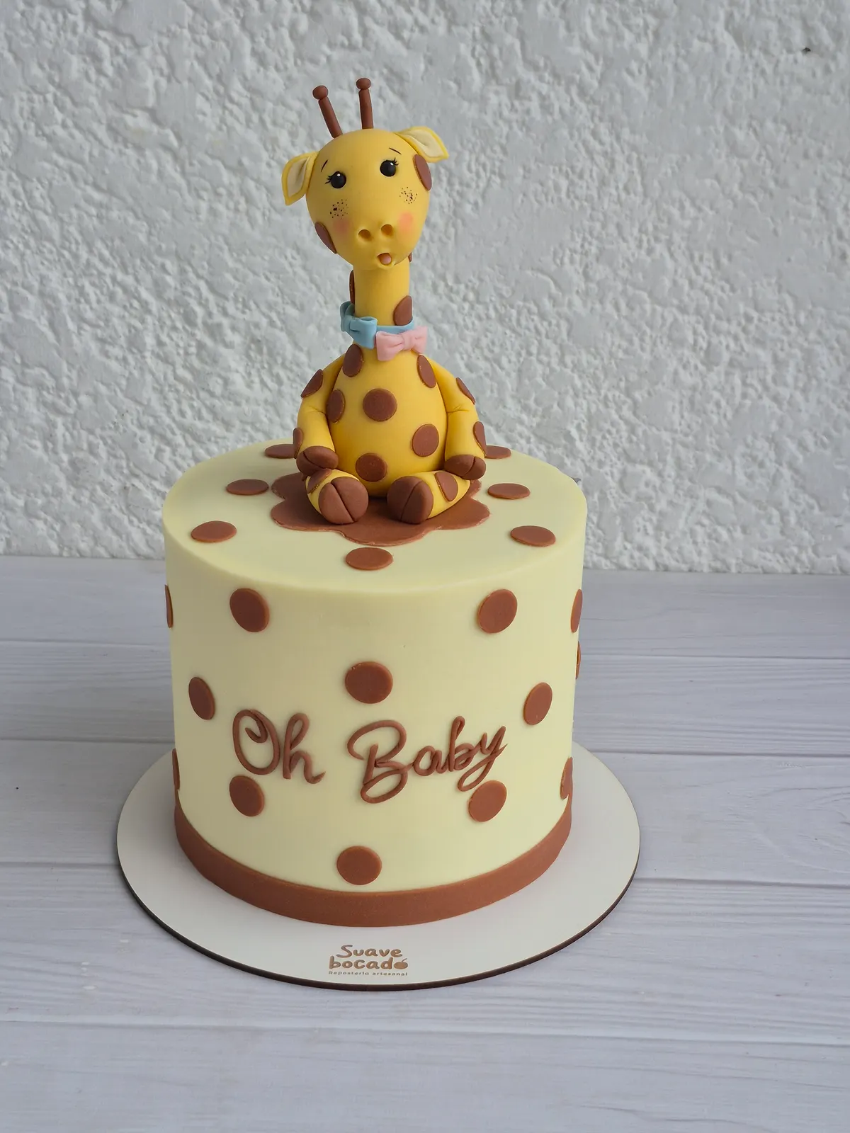Torta de baby shower color crema con lunares cafés, una jirafa y el mensaje Oh Baby