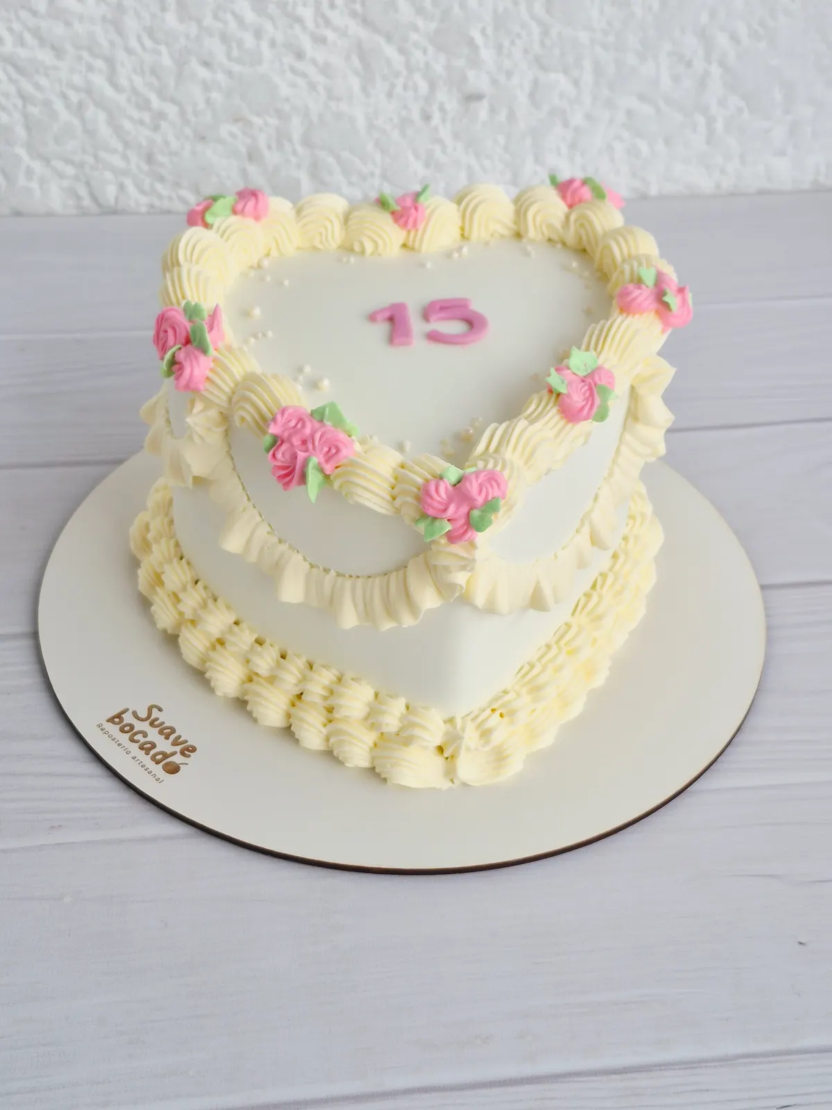 Torta de 15 años en forma de corazón con bordes de crema y rosas pequeñas