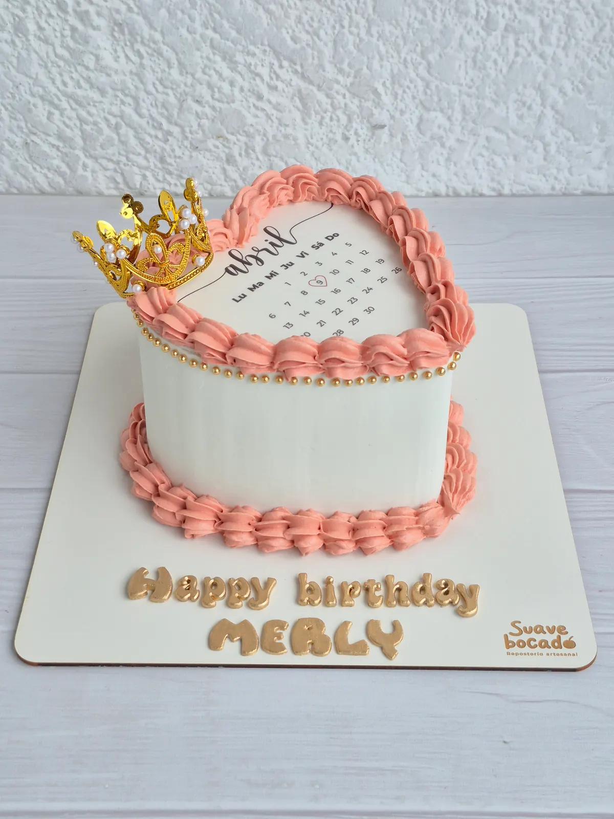 Torta rosada en forma de corazón con un calendario de abril, corona dorada y el nombre Merly