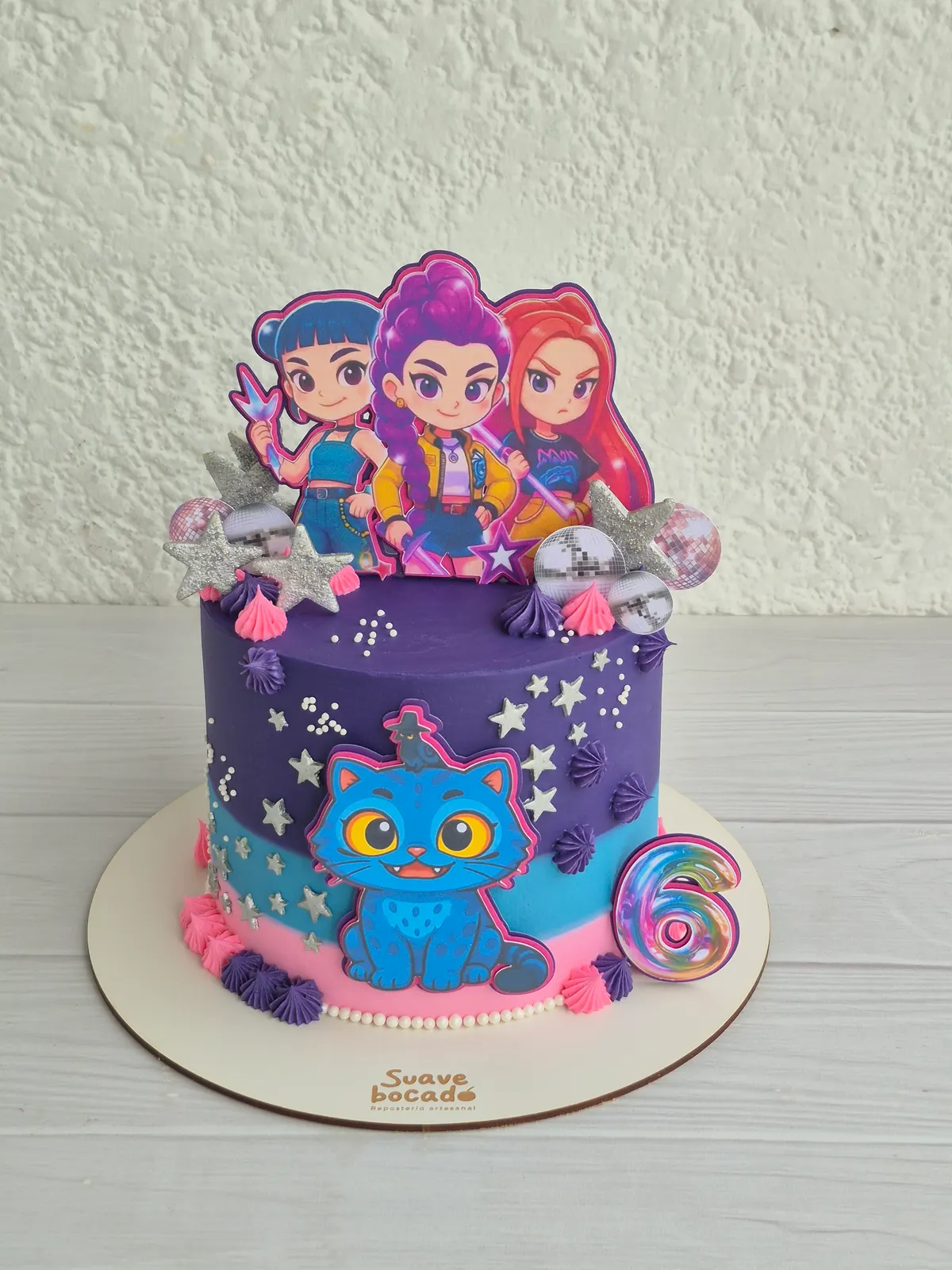 Torta morada con estrellas, un gatito azul, tres chicas ilustradas y un 6 en el borde