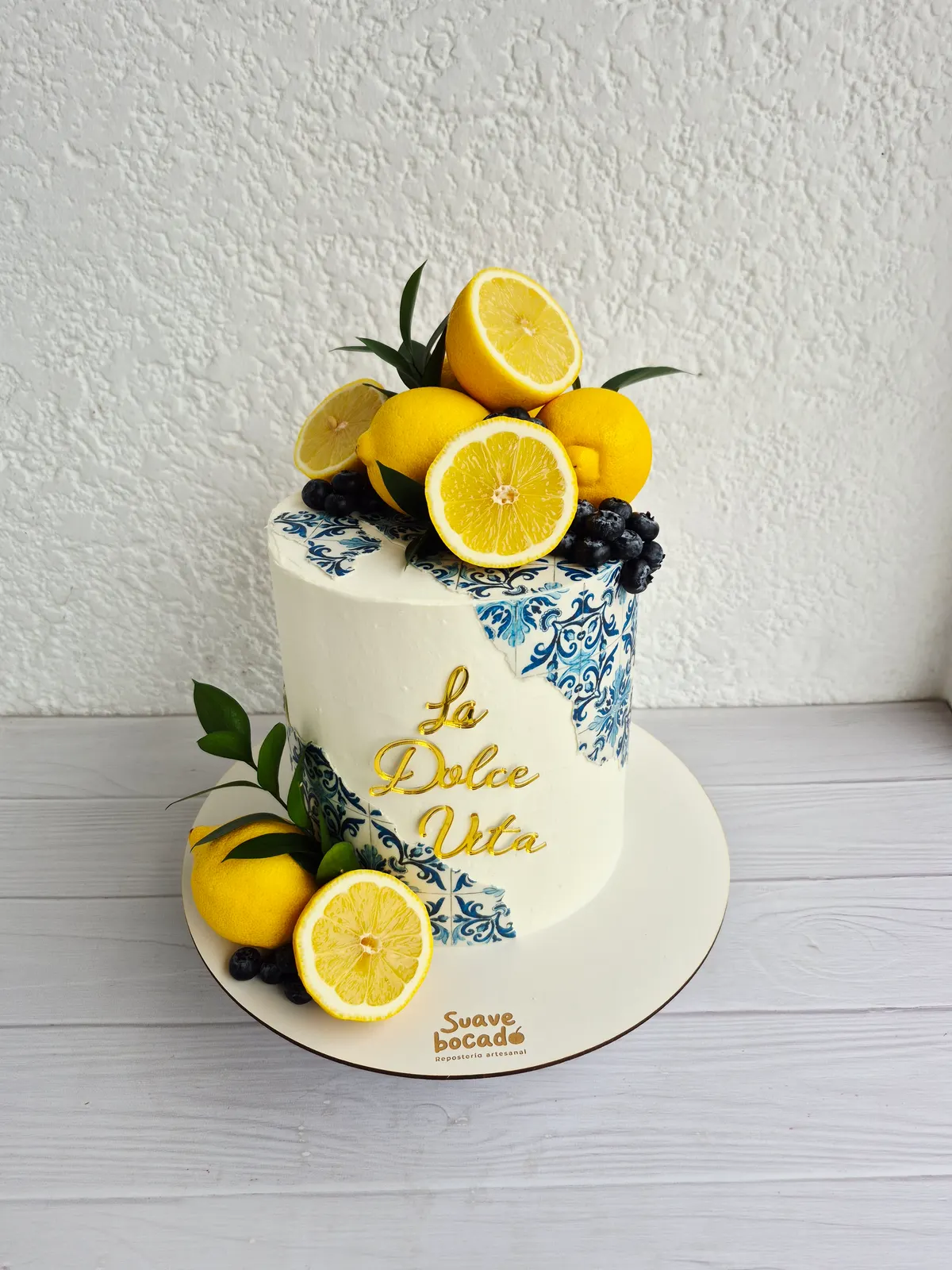 Torta blanca con limones, arándanos, detalles de cerámica azul y el texto La Dolce Vita